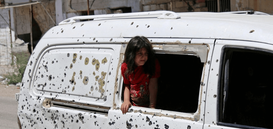 طفلة تنظر من حافلة مليئة بعيارات نارية في منطقة سيطر عليها الثوار في مدينة درعا، جنوبي سورية (2017)
