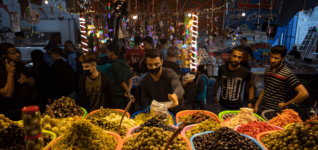 بائع فلسطيني يرتدي كمامة كحماية ضد انتشار الفيروس التاجي أثناء بيعه للمخللات في سوق الزاوية، بمدينة غزة، 28 نيسان 2020