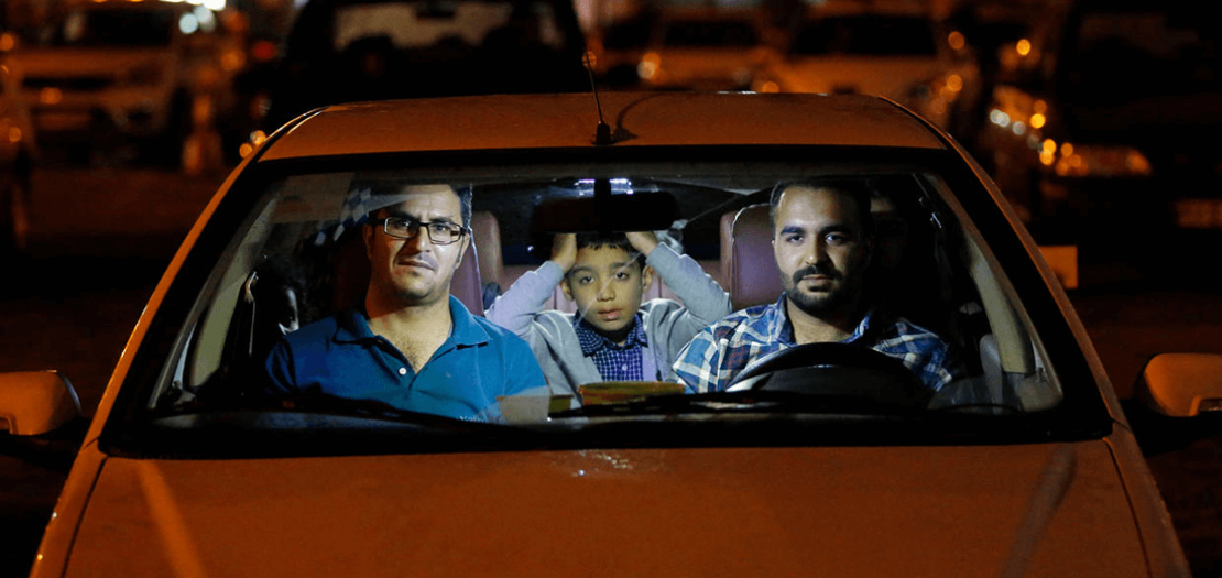 إيرانيون يتابعون من داخل سيارتهم شعائر دينية خلال شهر رمضان وسط أزمة فيروس كورونا، في مرآب سيارات في طهران في 30 نيسان 2020