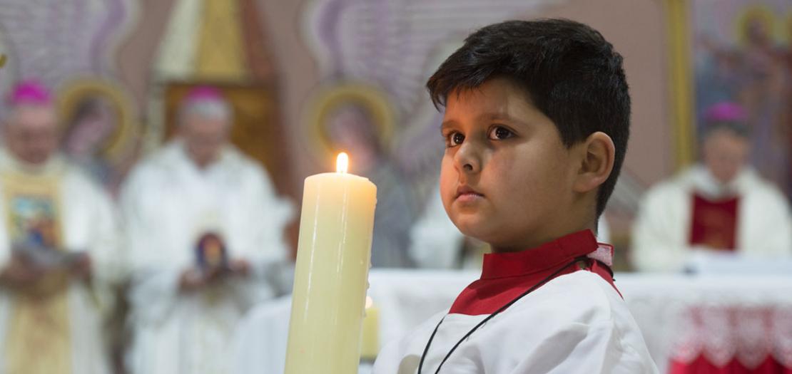 طفل فلسطيني يحمل شمعة خلال مشاركته في قداس الأحد بكنيسة العائلة المقدسة للاتين في مدينة غزة، 12 كانون الثاني 2020 (Mazur/cbcew.org.uk)