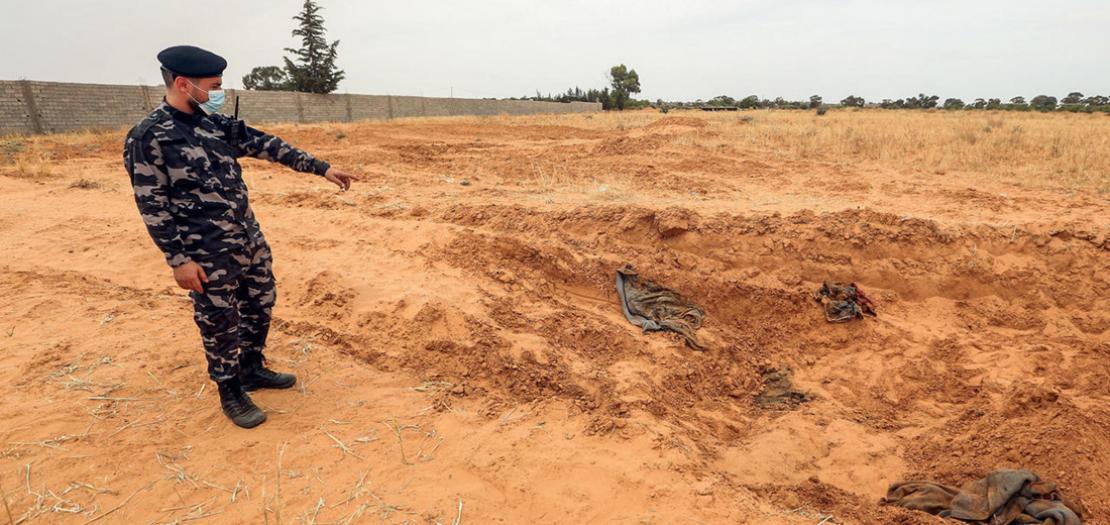 عضو من قوات الأمن التابعة لوزارة الداخلية في حكومة الوفاق الوطني الليبية يُشير إلى موقع يُشتبه في أنه مقبرة جماعية في ترهونة، 11 حزيران 2020