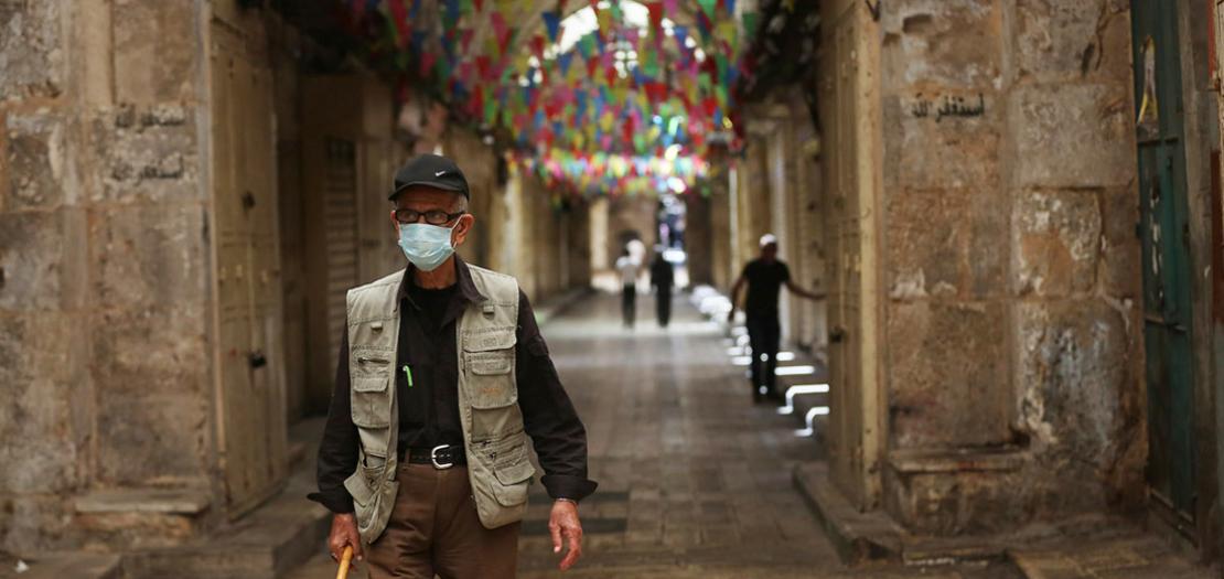 مواطن فلسطيني يسير في أحد شوارع نابلس، بعد قرار الحكومة إغلاق المدينة لمدة 48 ساعة لمساعدة الطواقم الطبية في حصر المخالطين للمصابين بفيروس كورونا ، 21 حزيران 2020(عدسة: أيمن نوباني / وفا)