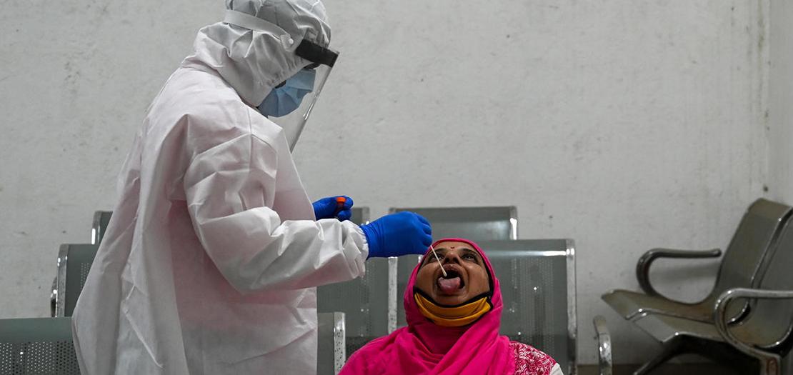 ممرض يجري فحصًا لكشف فيروس كورونا المستجد لامرأة في مومباي، 1 كانون الأول 2020