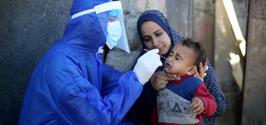 عامل طبي فلسطيني يجري اختبار الكشف عن فيروس كورونا لطفل (رويترز)