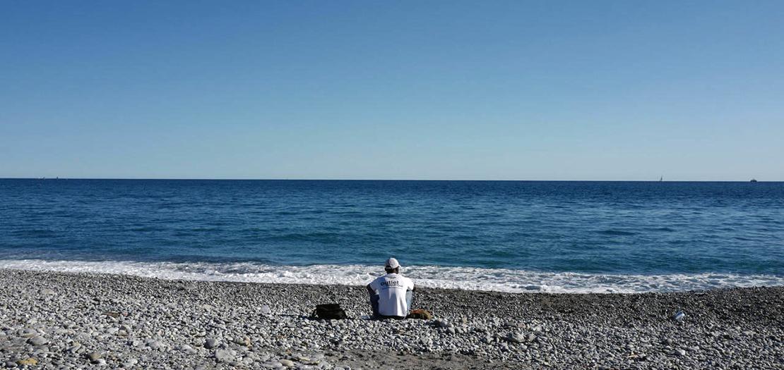مهاجر جالس على الشاطئ في مدينة فنتيميليا الإيطالية، 5 آب 2020