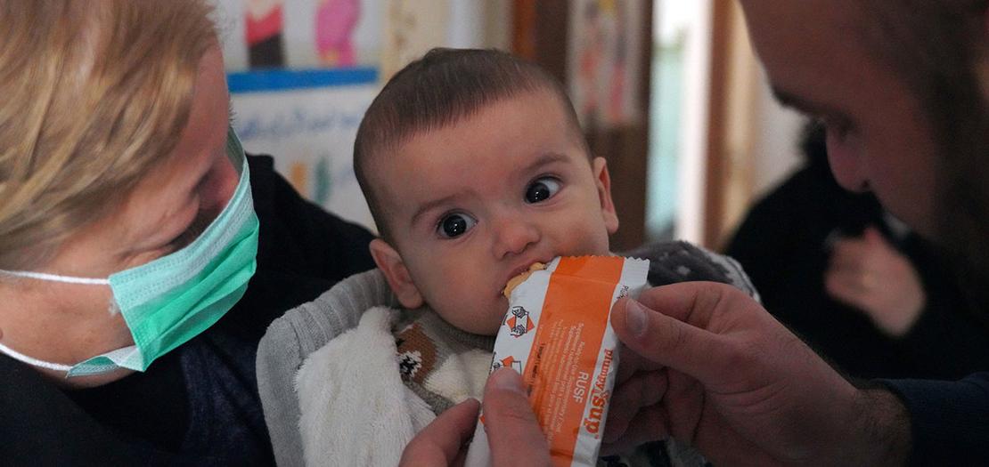 طفل يبلغ من العمر تسعة أشهر يأكل معجون الفول السوداني المغذي في عيادة في طرطوس بسورية