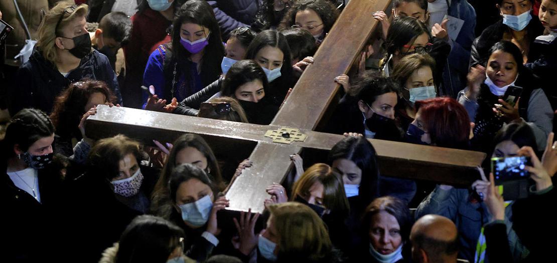 مسيحيون يحملون صليبًا خشبيًا لدى وصولهم إلى كنيسة القيامة بعد أن ساروا على درب  الآلام في بلدة القدس القديمة في يوم الجمعة العظيمة، 2 نيسان 2021