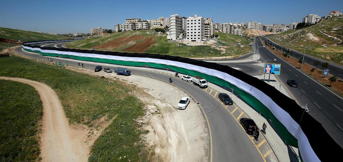 عمّال في أمانة عمّان الكبرى يضعون علمًا بطول 2132 في أحد شوارع العاصمة الأردنية في 15 نيسان 2021 في مسعى لدخول موسوعة غينيس للأرقام القياسية