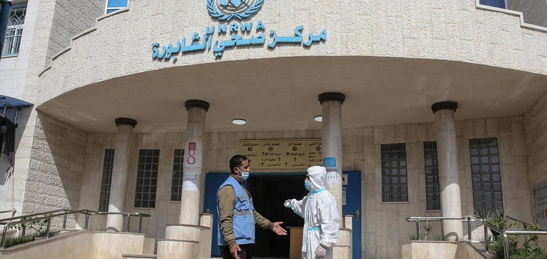 عاملون صحيون فلسطينيون خارج مركز صحي تديره وكالة الأمم المتحدة لإغاثة وتشغيل اللاجئين الفلسطينيين (الأونروا) في مخيم رفح للاجئين جنوب قطاع غزة، في 8 نيسان 2021