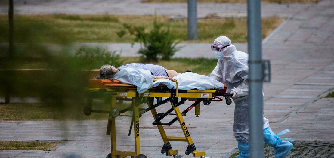عامل طبي ينقل امرأة الى المستشفى حيث يعالج المصابون بكورونا في كوموناركا قرب موسكو في 30 حزيران 2021.