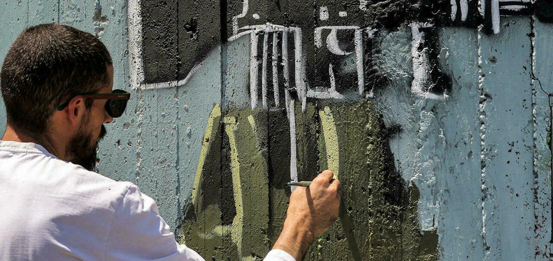 فنان الغرافيتي الفلسطيني تقي سباتين يرسم على الجدار الفاصل بين اسرائيل والضفة الغربة المحتلة في بيت لحم في 30 حزيران 2021