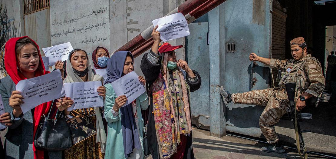 عنصر من حركة طالبان يراقب أفغانيات يرفعن لافتات خلال تظاهرة للمطالبة بحقوقهن أمام وزارة شؤون المرأة سابقا في كابول في 19 أيلول 2021