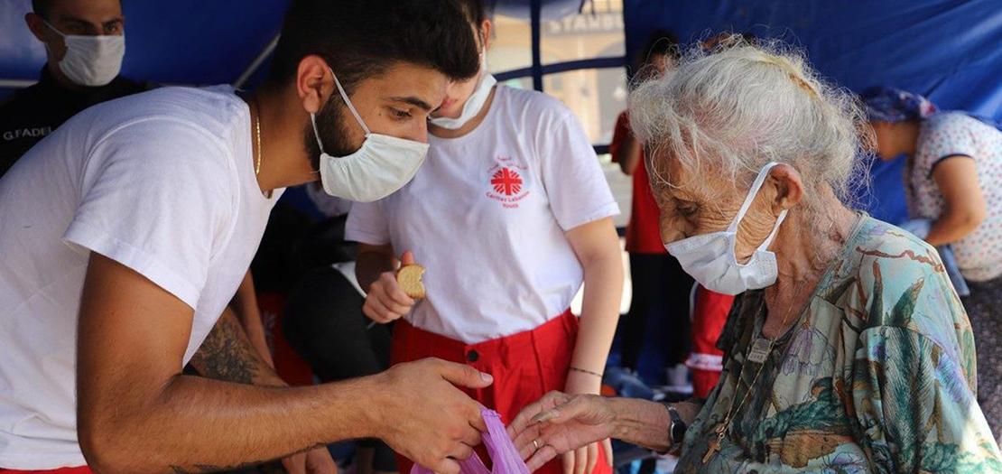 متطوع في كاريتاس لبنان يقدّم مساعدة لمسنّة