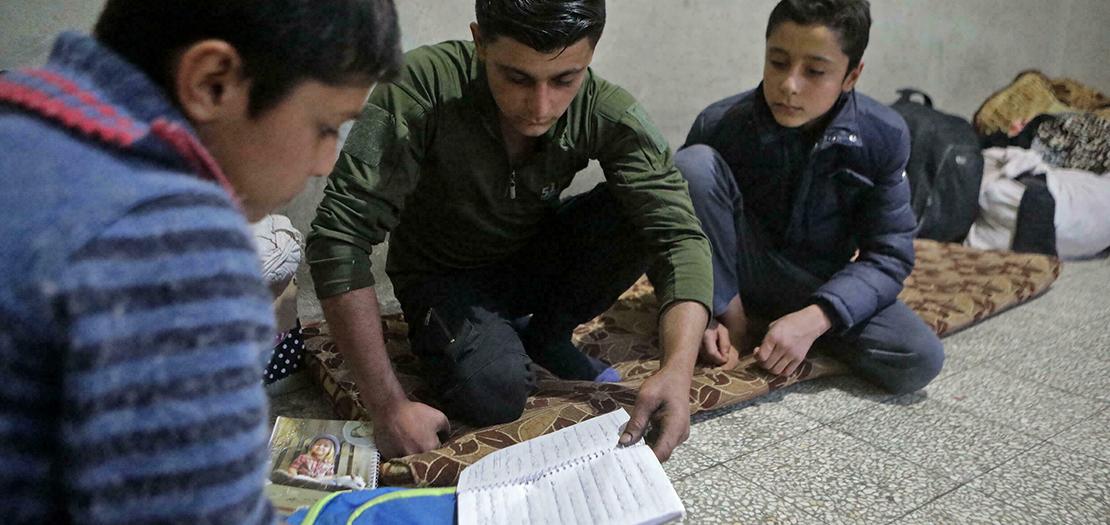 الطفل السوري محمد مخزوم يساعد شقيقيه في واجباتهم المنزلية في مدينة الباب في شمال سوريا، 19 تشرين الثاني 2021