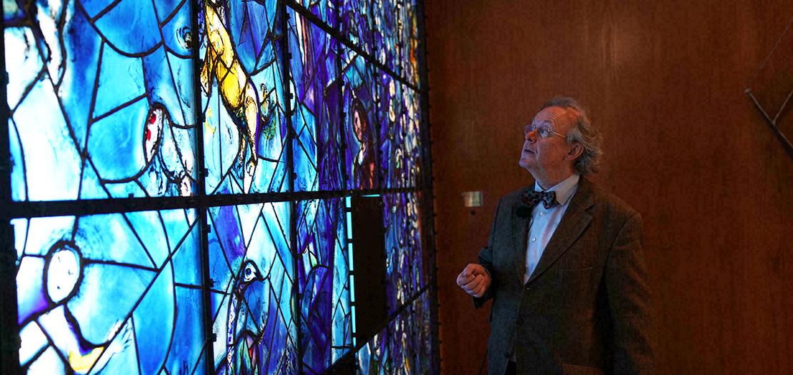 المسؤول عن الإشراف على مجموعة الأمم المتحدة الفنية فيرنر شميدت يقف أمام لوحة "النافذة" لمارك شاغال في مقر المنظمة الدولية في نيويورك، 3 تشرين الثاني 2021