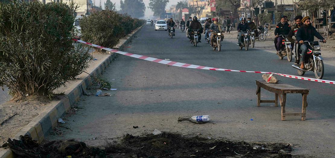 أشخاص يسيرون في 4 كانون الأول 2021 في مدينة سيالكوت الباكستانية بالقرب من الموقع حيث قُتل مدير مصنع سريلانكي وأضرمت النار في جثته بدعوى التجديف