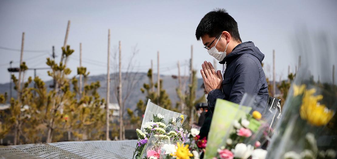 رجل يُصلّي في ايشينوماكي في اليابان أمام نصب تذكاري لضحايا الزلزال الذي تسبب بتسونامي