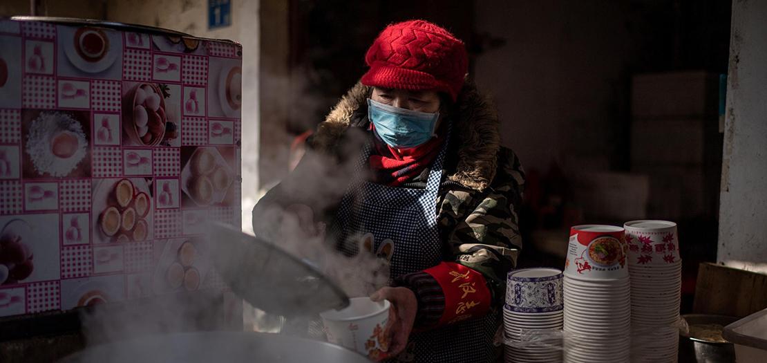 بائع يضع كمامة يحضر حساء في إحدى أسواق ووهان في الصين في 15 كانون الثاني 2021