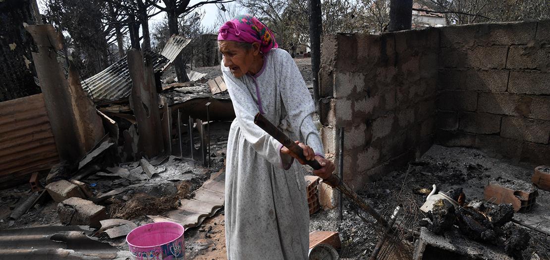 امرأة مسنّة بين أنقاض بيتها المحترق في مدينة القالة شمال شرق الجزائر بتاريخ 18 آب 2022