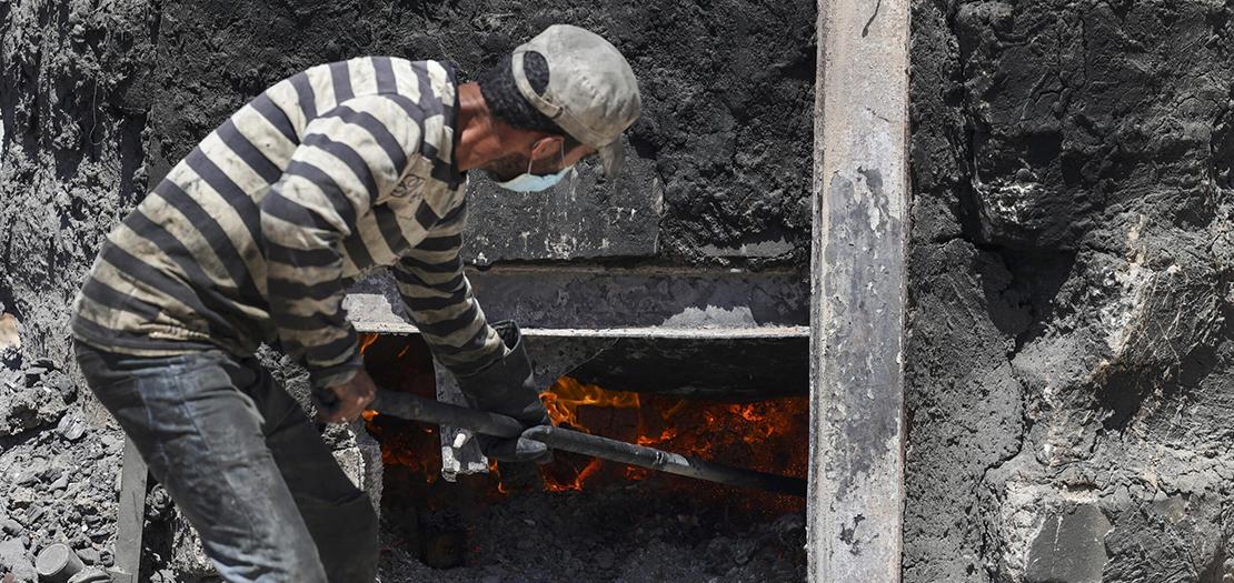 عامل فلسطيني يشعل النار في حوض يضم طنا من البلاستيك لإنتاج وقود في قطاع غزة، 23 آب 2022