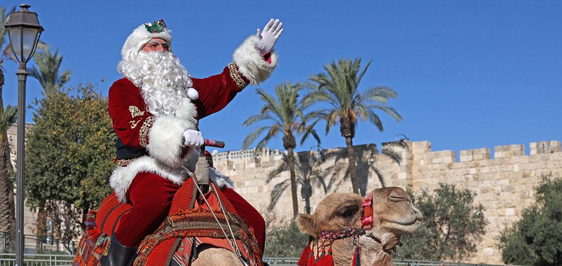 عيسى قسيسية مرتديًا زيّ بابا نويل أثناء ركوبه جملًا في البلدة القديمة في القدس الشرقية، 2 كانون الأول 2022