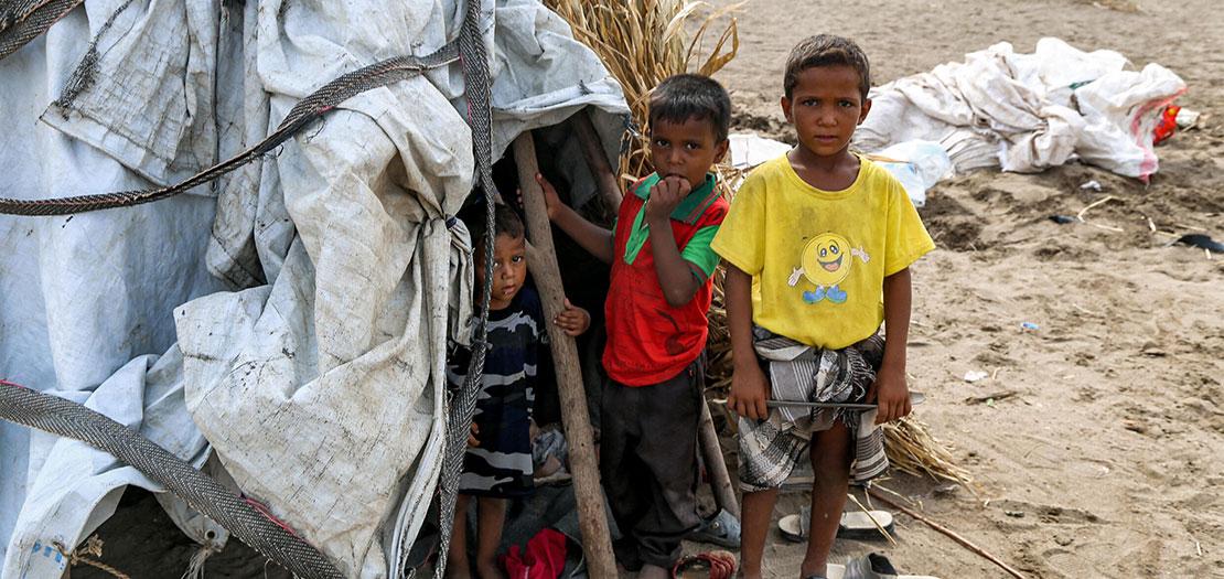 أطفال يقفون خارج خيمة في مخيم للنازحين تضرر من السيول في منطقة الجراحي التي دمرتها الحرب بمحافظة الحديدة غرب اليمن