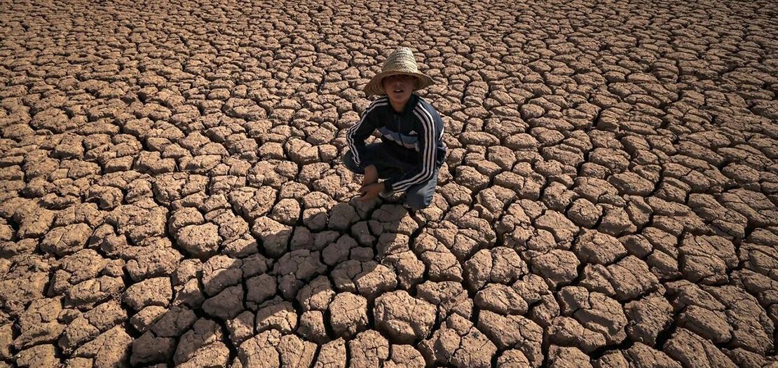 طفل يجلس على أرض مشققة بسبب الجفاف قرب سد المسيرة على بعد 140 كيلومترا من الدار البيضاء، 8 آب 2022