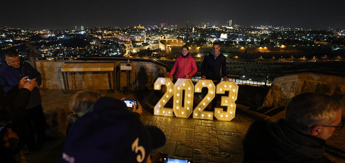 صورة مؤرخة في 31 كانون الاول 2022 لشخصين أمام لاقتة مضيئة بأرقام العام الجديد في جبل الزيتون في القدس