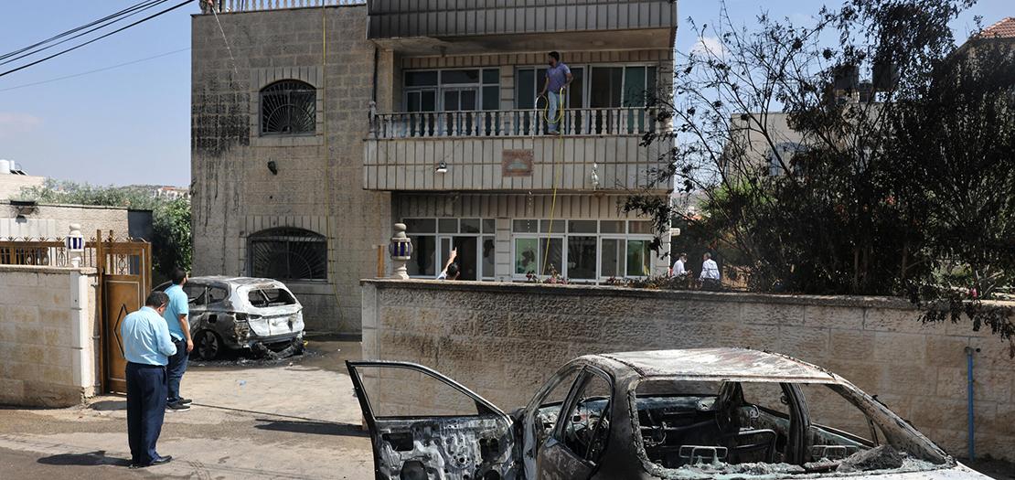 فلسطينيون يقفون قرب مركبات محترقة وسط تصاعد هجمات المستوطنين على قرية ترمسعيا، قرب رام الله، 21 حزيران 2023