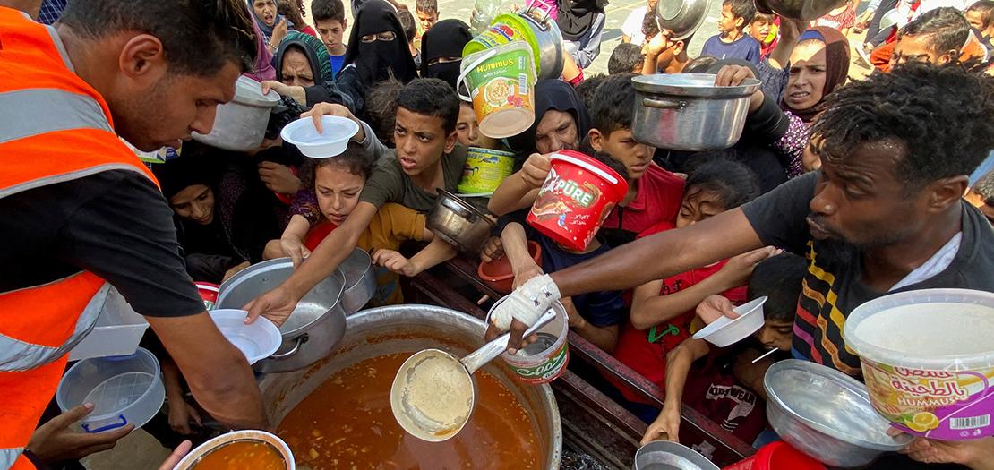 الفلسطينيون، الذين فروا من منازلهم بسبب الغارات الإسرائيلية، يتجمعون للحصول على حصتهم من المواد الغذائية الخيرية، في رفح