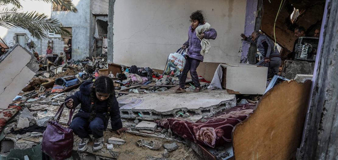 طفلتان تحملان أغراضهما وسط منزل دمرته غارة إسرائيلية في رفح السبت