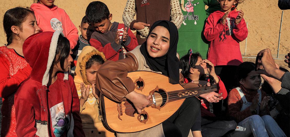 رؤى حسونة تعزف الموسيقى للأطفال الفلسطينيين في مخيم للنازحين في رفح في 18 كانون الأول 2023