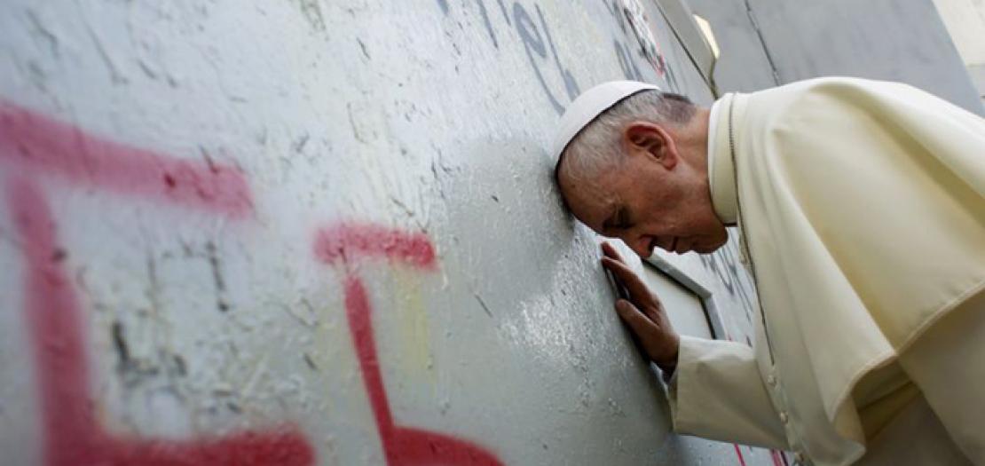 البابا فرنسيس يلمس الجدار الذي يفصل إسرائيل عن الضفة الغربية، وهو في طريقه للاحتفال بالقداس في ساحة المهد بجوار كنيسة المهد في بيت لحم، أيار 2014