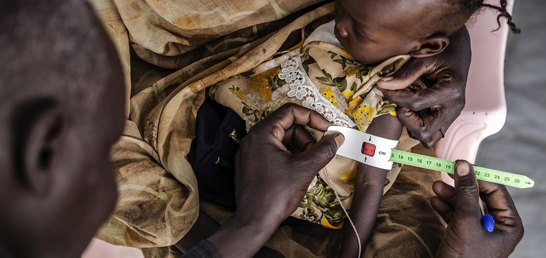 عامل في مجال الصحة يقيس حجم ذراع طفلة سودانية