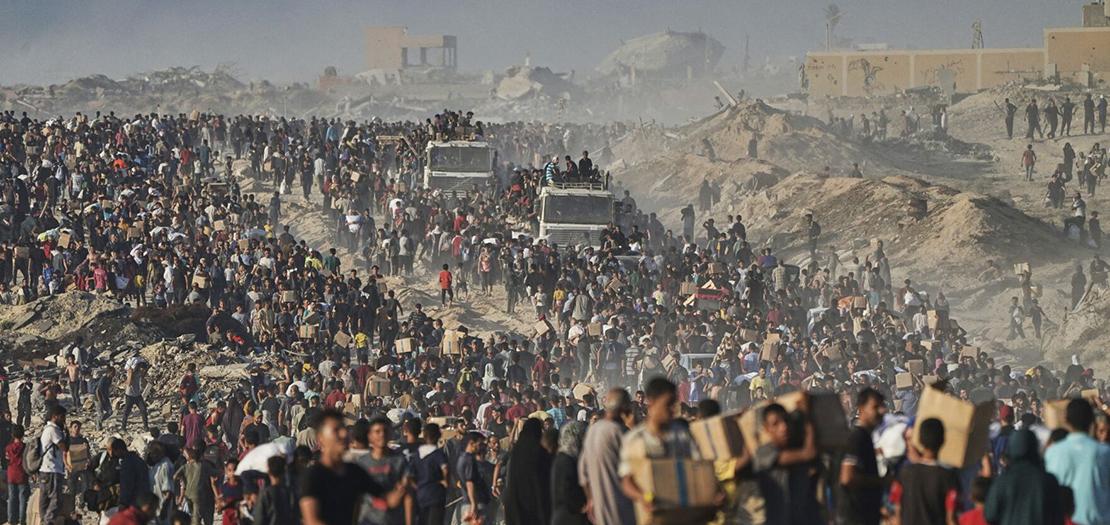 فلسطينيون يحملون أكياسًا وصناديقًا من الطعام والمساعدات الإنسانيّة التي تم تفريغها من قافلة برنامج الغذاء العالمي التي كانت متجهة إلى مدينة غزة، الاثنين 16 حزيران 2025